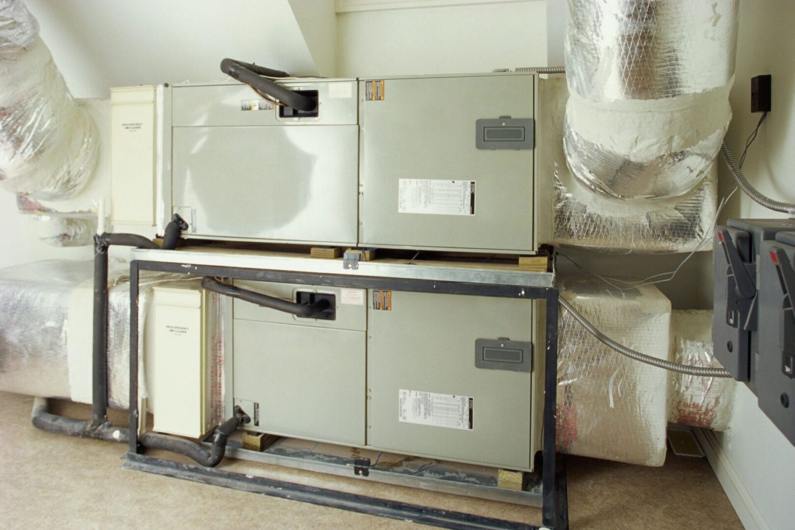 Industrial air handling units installed in a mechanical room with large ductwork and insulation visible.